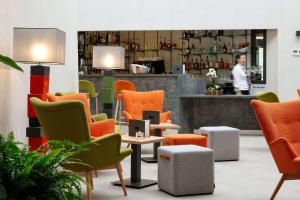 a lobby with colorful chairs and a person in the background at Best Western Plus Hôtel Escapade Senlis in Senlis