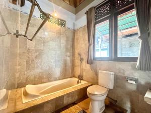 a bathroom with a tub and a toilet at Bali Moon Guest House in Ubud