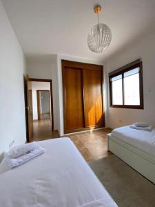 a bedroom with two white beds and a chandelier at El Olivar Corralejo Sun & Beach in Corralejo