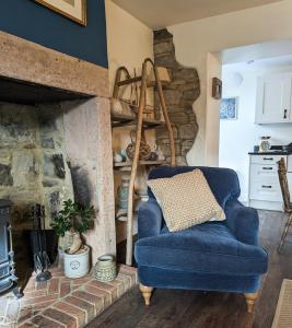 a blue chair in a living room with a fireplace at Rose Cottage in Beadnell