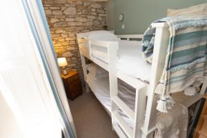 two bunk beds in a room with a stone wall at Rose Cottage by Coast & Country Stays in Beadnell