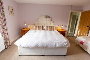 a bedroom with a large white bed with a wooden headboard at Rose Cottage by Coast & Country Stays in Beadnell