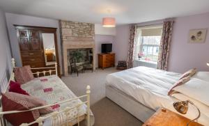 a bedroom with a bed and a chair and a fireplace at Rose Cottage by Coast & Country Stays in Beadnell