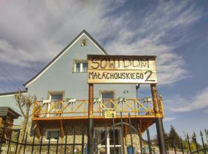 a sign in front of a building with a house at Sowi Dom - Jugów in Jugów