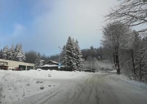 a road covered in snow with trees and a building at Sowi Dom - Jugów in Jugów +38 photos