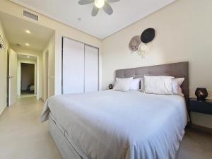 a bedroom with a large white bed with a ceiling fan at La Serena Apartment - 3410 in Los Alcázares