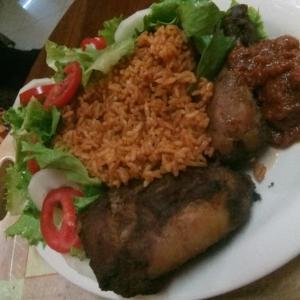 a plate of food with rice and a salad at Etna Apartments in Takoradi
