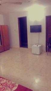 a living room with a white room with a television at Etna Apartments in Takoradi