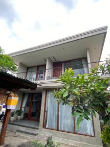 une maison avec un balcon et un arbre dans l'établissement Cuan House Ubud, à Ubud