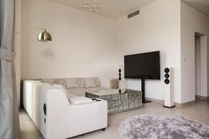 een witte woonkamer met een witte bank en een tv bij Luxury feel in Ras al Khaimah