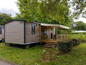 a tiny house in a yard with a porch at Camping Fleur d'Oleron in Saint-Pierre-dʼOléron