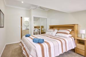 a bedroom with a large bed with a striped blanket at Moonya Avocado Farm Cottage - with early check-in in Mount Tamborine