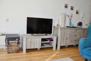 a television on a wooden stand in a living room at Appartement Badhotel 301 in Callantsoog