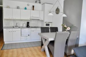 a kitchen with white cabinets and a wooden table at Appartement Badhotel 301 in Callantsoog