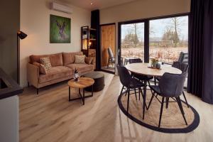 uma sala de estar com um sofá, uma mesa e cadeiras em Hofparken De Bergvennen em Lattrop
