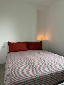 un letto con cuscini rossi in una camera bianca di Ambra House a Trezzano sul Naviglio
