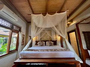 a bedroom with a bed with a canopy at Bali Moon Guest House in Ubud
