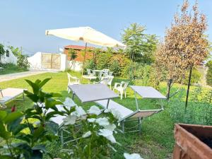 a garden with tables and chairs and an umbrella at IL DIAMANTE SUL MARE in Diamante