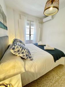 1 dormitorio con cama con almohadas y ventana en www Casa Quili Cádiz com en Cádiz