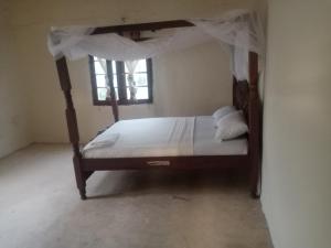 a bedroom with a canopy bed with a window at Seafront House in Lamu