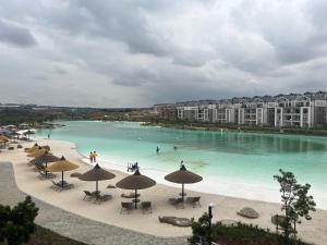a beach with chairs and umbrellas and people in the water at Lagoon Facing Apartment in Midrand
