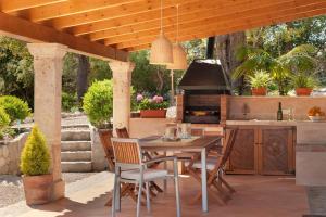 an outdoor kitchen with a table and chairs under a pergola at La Salve dalt in Pollença
