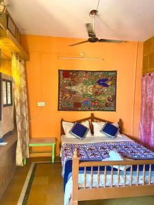 a bedroom with a bed with an orange wall at Little Prince Home Stay in Jaisalmer