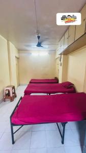 fila de camas en una habitación con sábanas rojas en Santacruz east, en Bombay