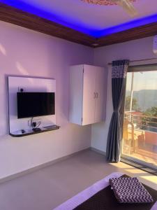 a room with a tv and a room with a balcony at Hotel Mahabaleshwar Mount View in Mahabaleshwar