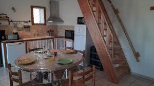 uma cozinha com uma mesa com cadeiras e uma escada em maisonnette le cabanon em Sainte-Jalle