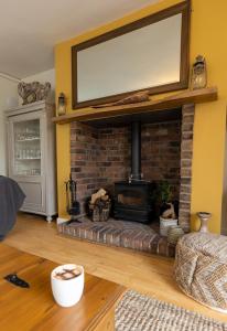 a living room with a brick fireplace with a flat screen tv at Church Cottage in Beadnell