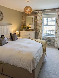a bedroom with a large white bed and a window at Church Cottage by Coast & Country Stays in Beadnell