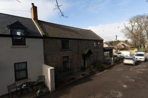 a brick house with cars parked in a parking lot at Church Cottage by Coast & Country Stays in Beadnell