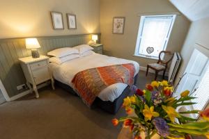 a bedroom with a bed and a vase of flowers at Church Cottage by Coast & Country Stays in Beadnell
