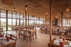 a restaurant with wooden tables and chairs and windows at Sanctuary Resort, Chitwan National Park, Nepal in Chitwan