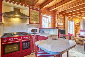 uma cozinha com um fogão vermelho e uma mesa em Chalet le Serac em Gresse-en-Vercors