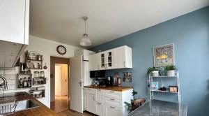 una cocina con armarios blancos y una pared azul en Chez Catherine, en Fontenay-le-Fleury