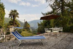 une terrasse avec une table, des chaises et un parasol dans l'établissement Wild Valley Ticino Vista in Valle Onsernone, à Auressio