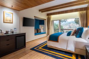 a bedroom with a large bed and a large window at Moksha Himalaya Spa Resort in Kasauli
