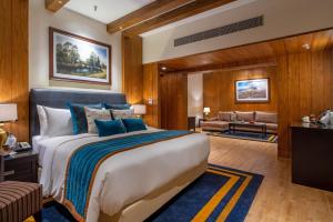 a bedroom with a large bed and a living room at Moksha Himalaya Spa Resort in Kasauli