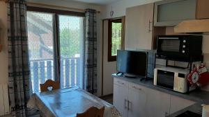 Il comprend une cuisine avec une table, une télévision et une fenêtre. dans l'établissement Bernex T2 toute saison au pied des pistes, à Bernex