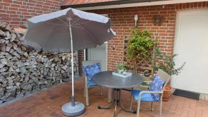 - une table et des chaises avec un parasol sur la terrasse dans l'établissement Ferienwohnung Zum Lotsen, 45227, à Jemgum