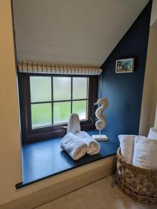 asiento junto a la ventana en una habitación con almohada y silla en Lindisfarne Cottage, en Beadnell