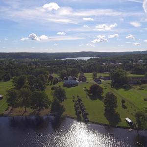 an aerial view of a house and a field next to a river at Svaneholm Hotel in Svanskog
