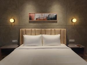 Una cama con almohadas blancas y dos luces por encima. en Olive Le Opera by Embassy Group en Bangalore