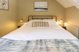 a bedroom with a large white bed with two lamps at The Hayloft in Beadnell