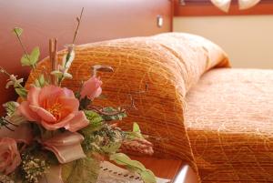 a vase of flowers on a table next to a bed at Locanda Canareggio in San Biagio di Callalta