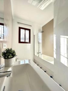 a white bathroom with a tub and a large mirror at Hispalis villa en Matalascañas in Matalascañas