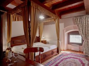 ein Schlafzimmer mit einem Himmelbett und einem Tisch mit Weingläsern in der Unterkunft Pipo Várkastély, Ozora in Ozora
