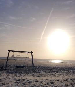 eine Schaukel am Strand mit der Sonne im Hintergrund in der Unterkunft Haus Marrakesch in Borkum